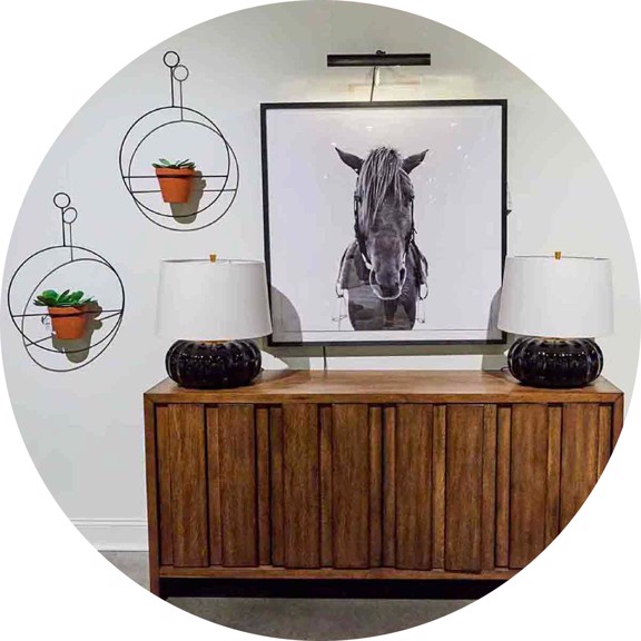 wooden console with a horse painting, lamps and hanging plants
